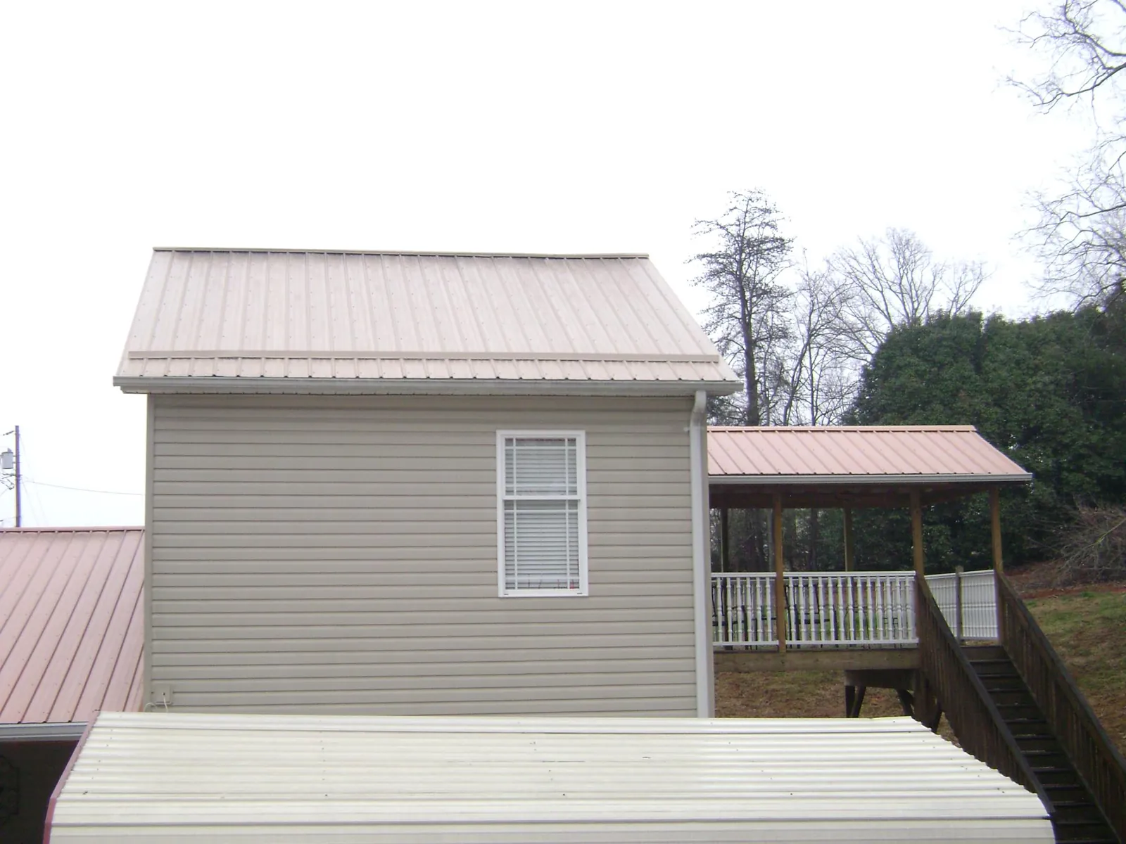 Tan metal roofs on a two story addition and attached porch, from a Roof Replacement job in Palmer